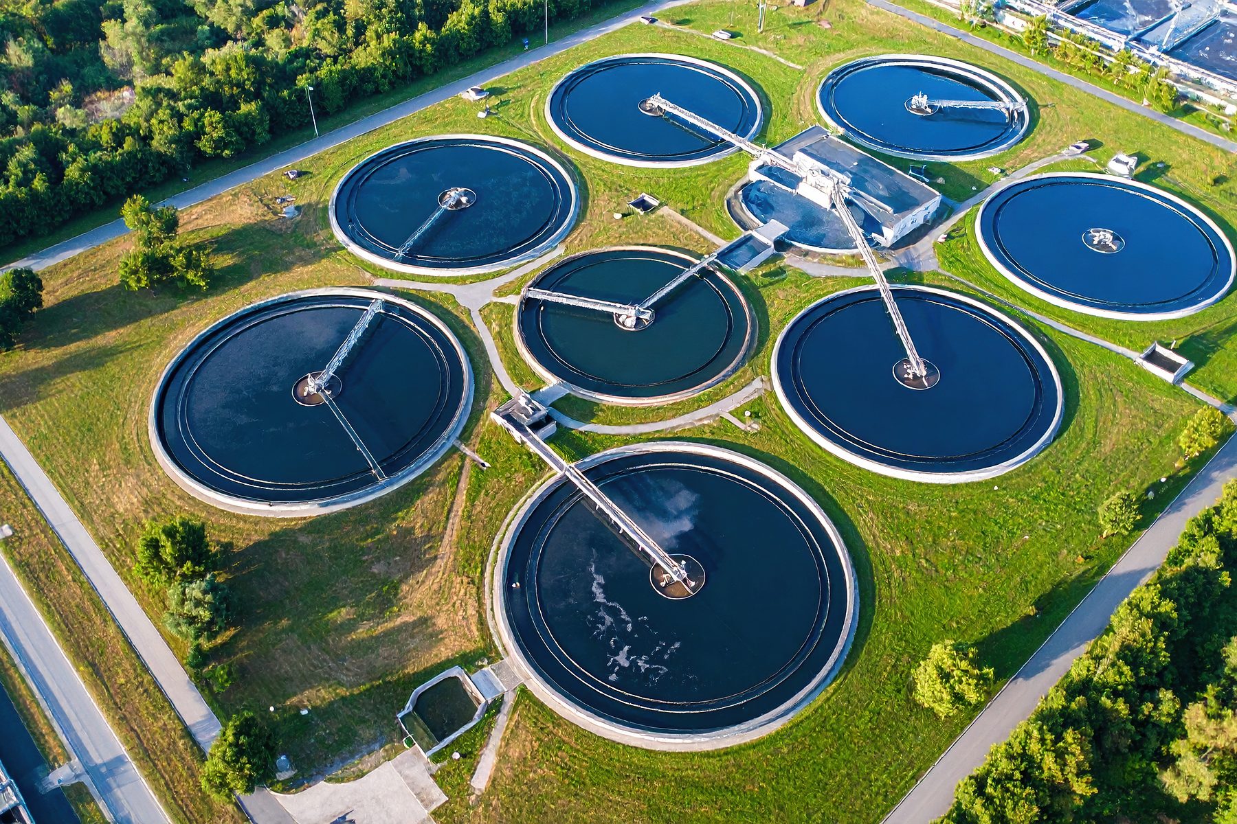 Aerial view of a wastewater treatment plant, showing circular clarifier tanks